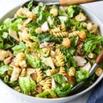 chicken caesar pasta salad in a bowl with salad tongs