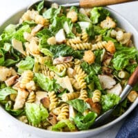 chicken caesar pasta salad in a bowl with salad tongs