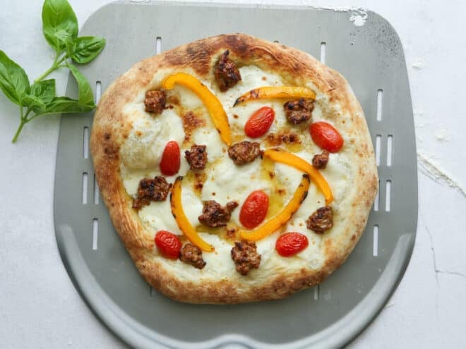 baked italian sausage pizza on pizza peel