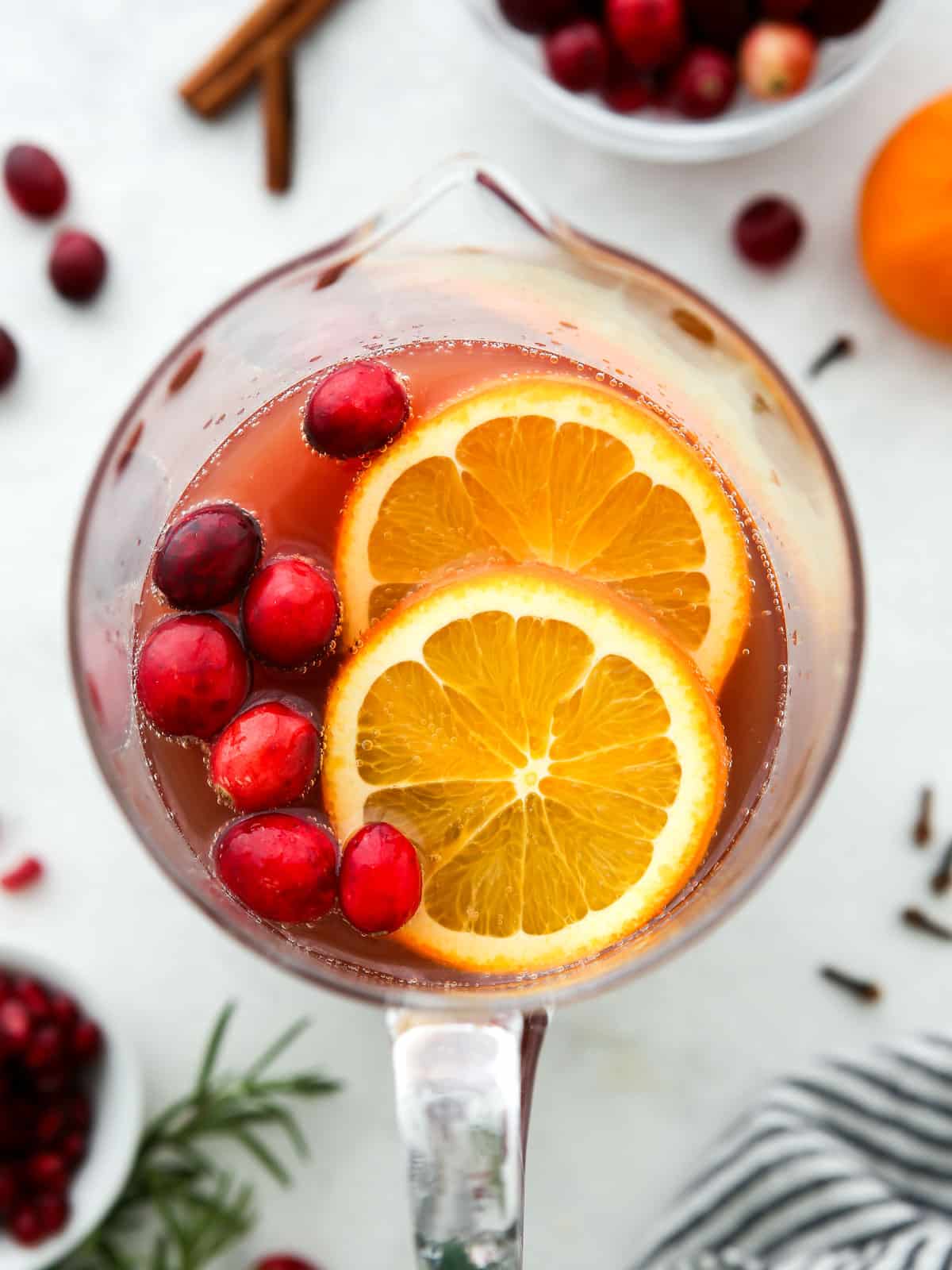 pitcher of holiday punch with cranberries and orange slices