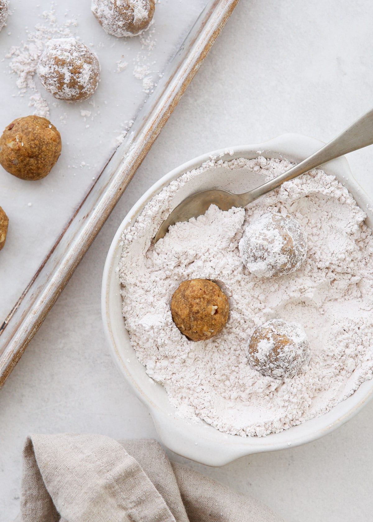 rolling baked snowballs in powdered sugar