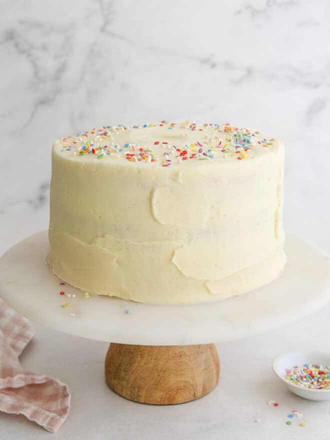 frosted vanilla layer cake on a cake stand