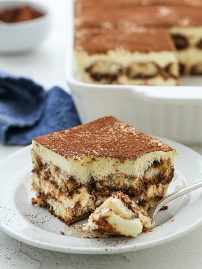 close up of bite taken out of tiramisu on a plate