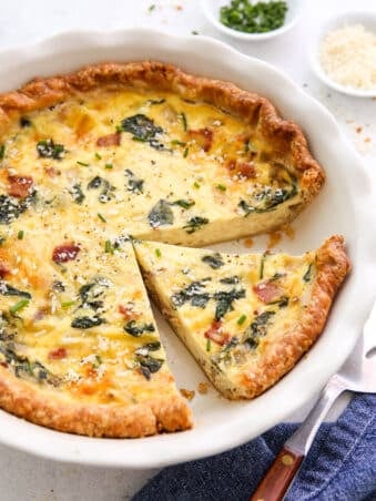 slicing baked spinach bacon quiche in pie dish