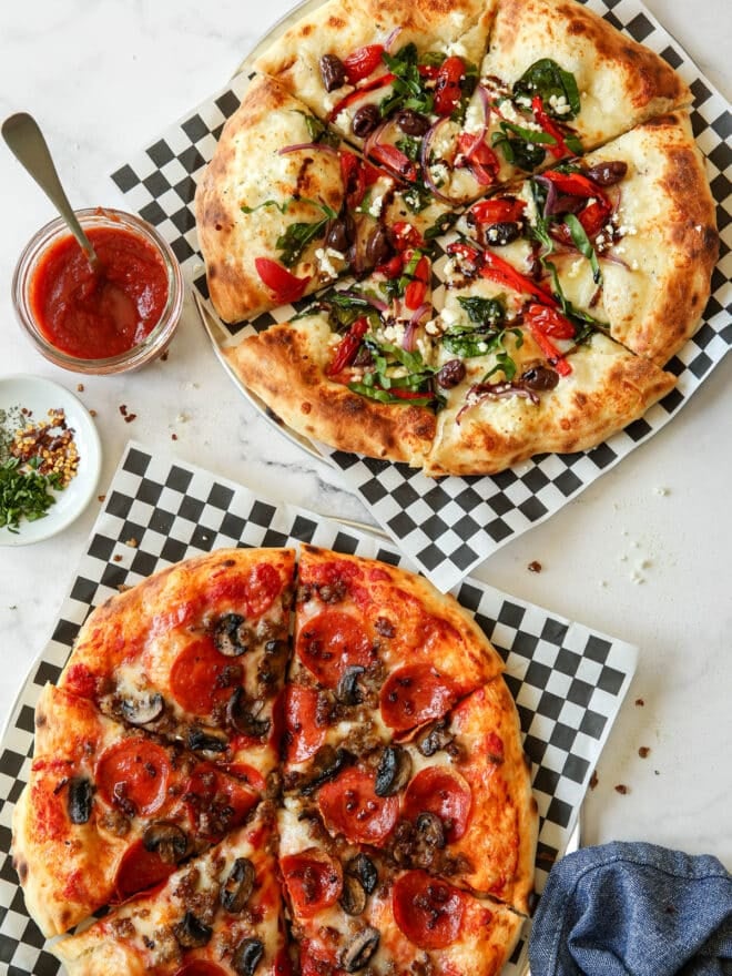 two homemade sliced pizzas on serving trays