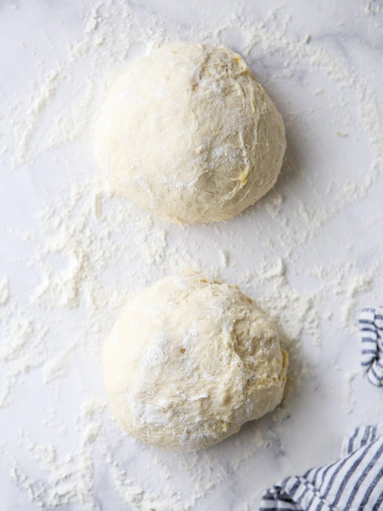 two rounds of pizza dough on floured counter