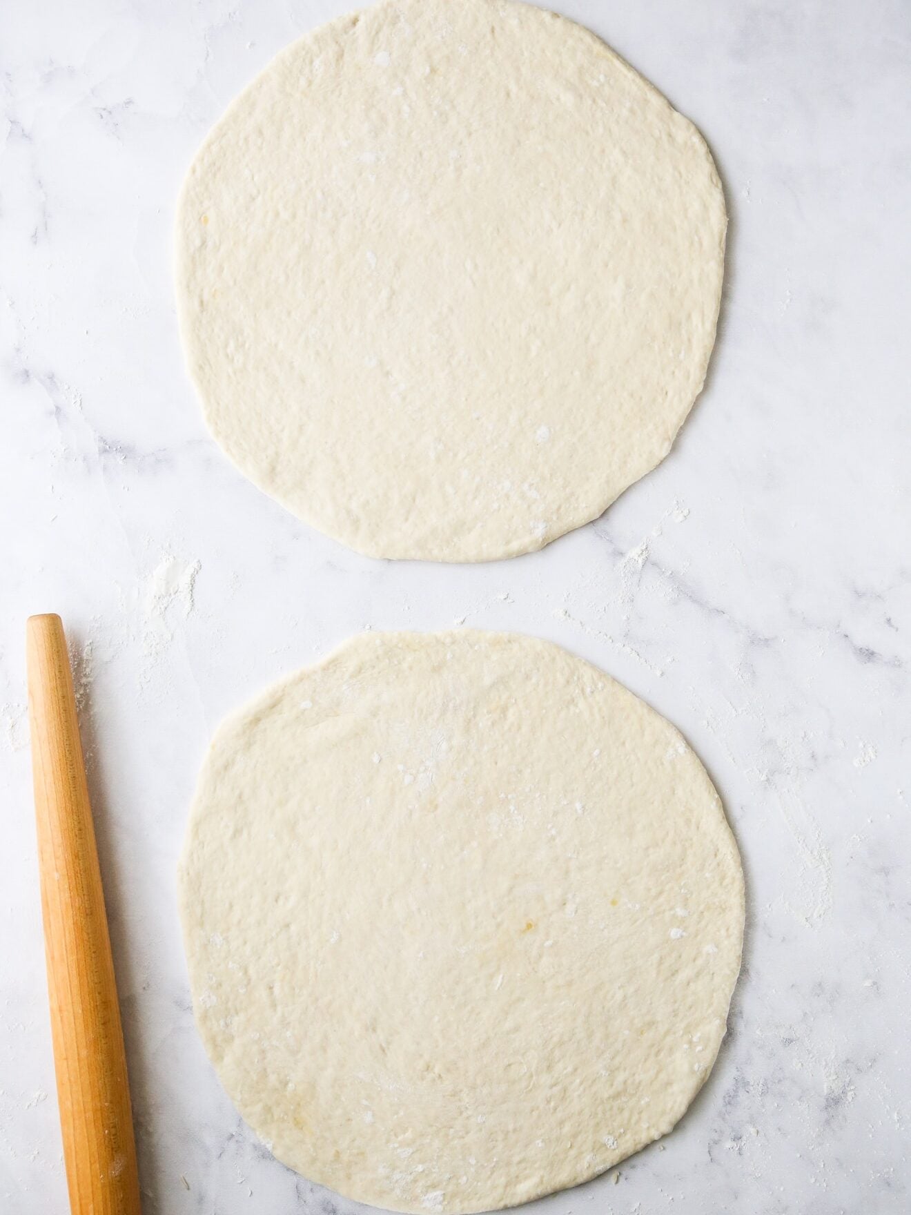 two rounds of pizza dough rolled out to make pizza